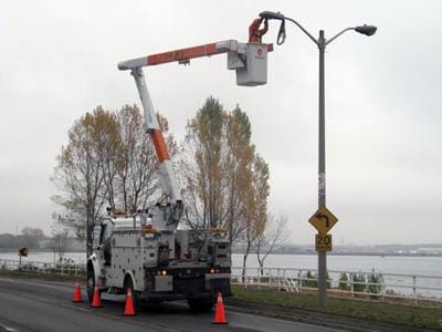 Person fixing a high street light with utility vehicle